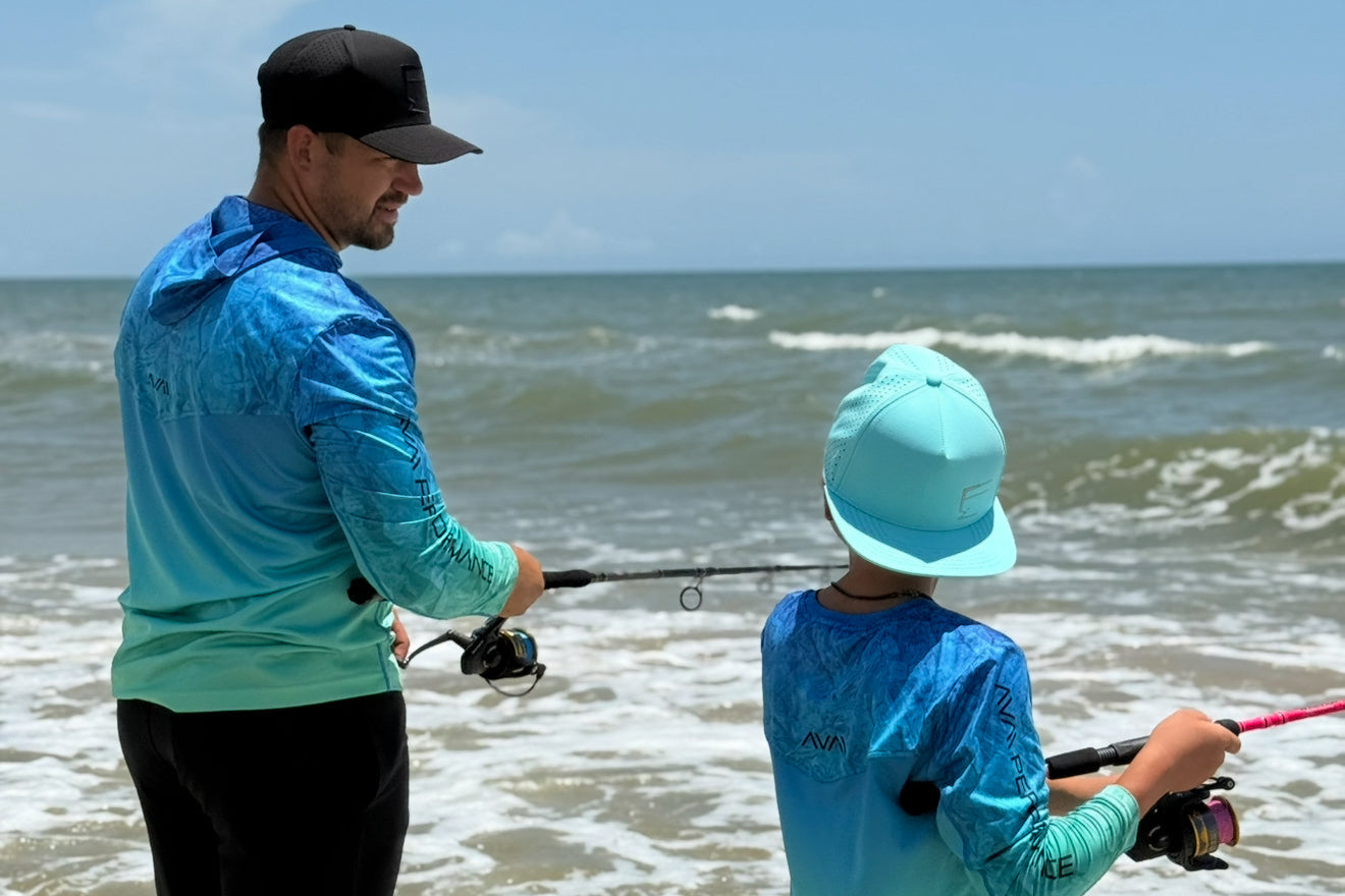 Man and child fishing in the ocean wearing matching blue shirts.